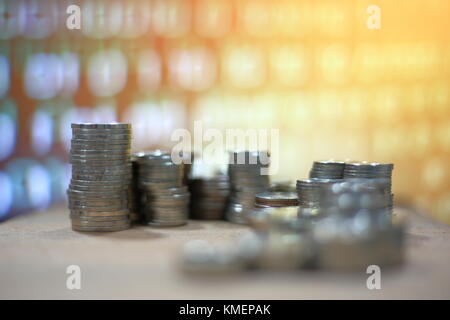 vintage digital economy coin pile stacked in to columns on wooden board. Digital binary code in the background. Declining chart poor economic. Hacker Stock Photo