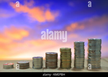 Coin pile, Thai baht stacking column.  Business, money, saving and financial concept. Twilight blue and red cloud sky. Stock Photo
