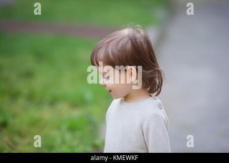 Portrait of a cute blond child with long hair, dressed in a beige sweater. A beautiful boy of three years. Stock Photo