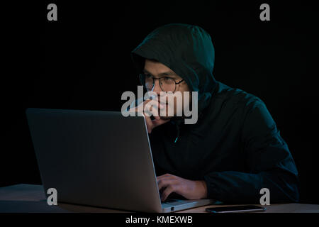 Asian hacker hacking computer network with laptop in dark. Cyber security concept Stock Photo