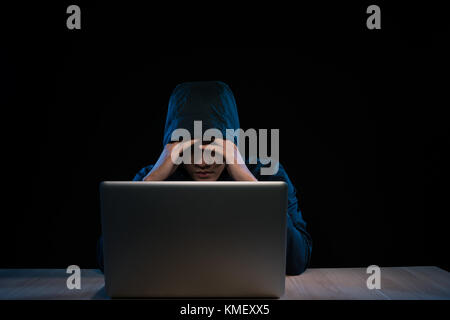Asian hacker hacking computer network with laptop in dark. Cyber security concept Stock Photo