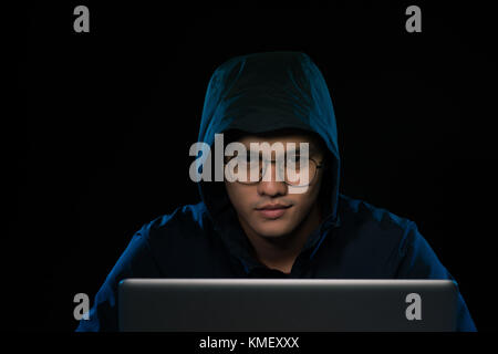 Asian hacker hacking computer network with laptop in dark. Cyber security concept Stock Photo