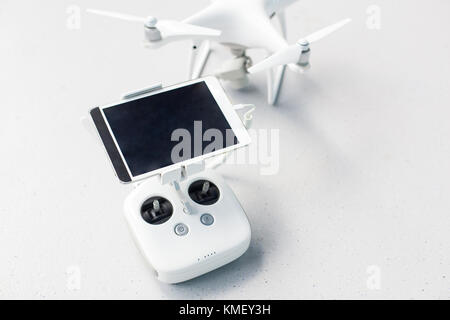 Drone with a remote control and a tablet on it on a gray concrete background. Quadcopter with camera ready to shoot video. Stock Photo