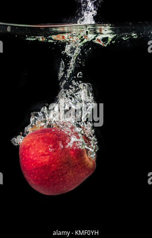 Apple falls into the water and makes a splash. Stock Photo