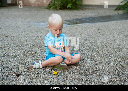 Three year old boy playing with gravel Stock Photo