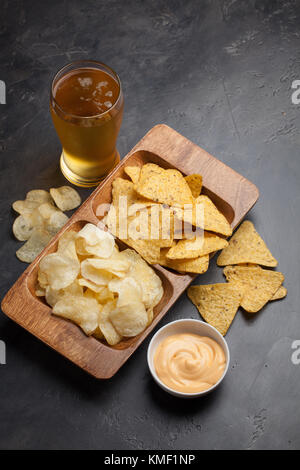 Beer in glasses closeup on the concrete table. Beer and snacks are chips and nachos with cheese souce top view. Copy space. Drink and snack for the fo Stock Photo