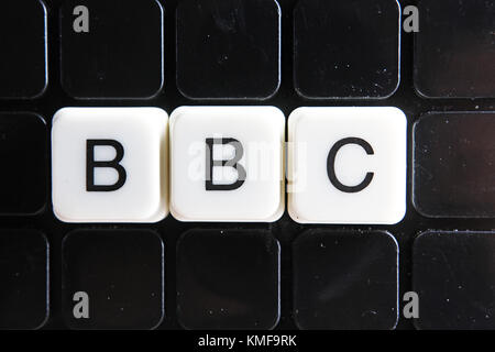 BBC text word crossword. Alphabet letter blocks game texture background. White alphabetical letters on black background. White educational toy block with words. Stock Photo