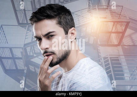 Serious young engineer feeling suspicious about the strange unsafe building Stock Photo