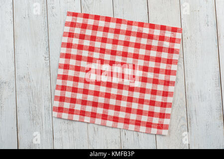 Red tablecloth on white wooden table background. Stock Photo