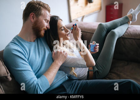 Romantic couple eating ice cream together and watching tv Stock Photo