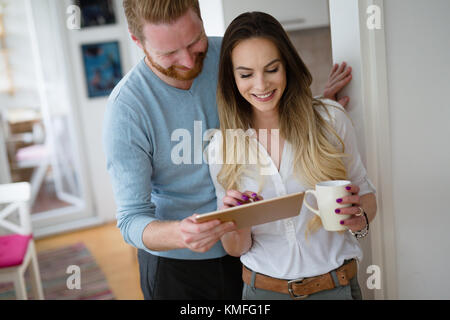 Happy couple using tablet and drinking coffee at home Stock Photo