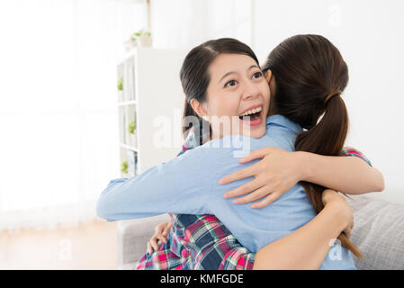 happy female friends hugging together in living room and cheerfully celebrate about the successful finished college class. Stock Photo