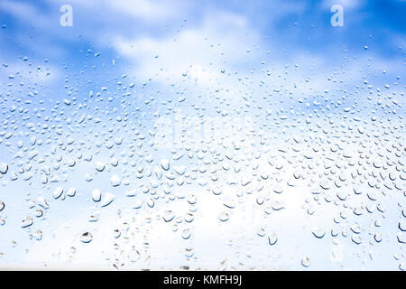 Rain drops on the glass in the background blurred blue cloudy sky. After raining concept Stock Photo