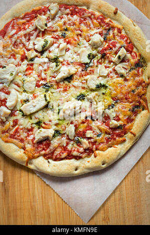 Pizza with chicken, cheese, green pesto, tomato sauce Stock Photo
