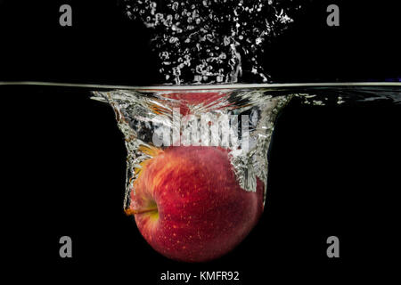 Apple falls into the water and makes a splash. Stock Photo