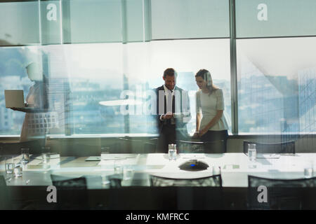 Businessman and businesswoman working, using digital tablet in urban conference room Stock Photo