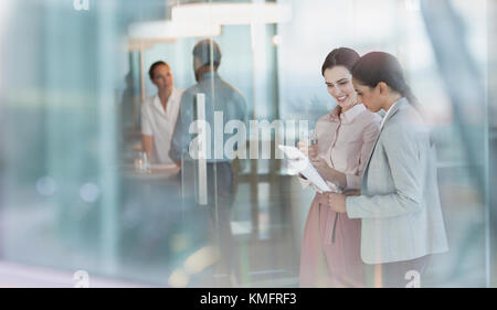 Businesswomen talking, reviewing paperwork in office Stock Photo
