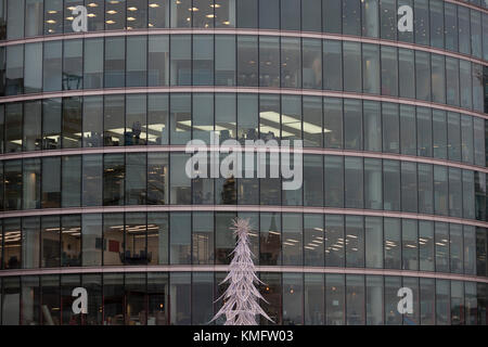 An artificial Christmas tree and the many storeys of corporate offices, on 6th December 2017, in London England. Stock Photo