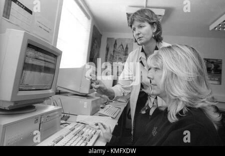Female inmate learning computer skills in education room assisted by prison tutor (standing) at HMP Winchester prison, Winchester, Hampshire, United Kingdom. 10 May 2001. Stock Photo