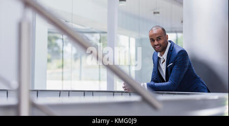 Portrait smiling businessman leaning on railing in office Stock Photo