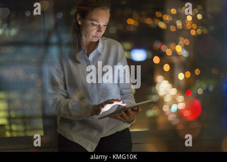 Businesswoman working late at digital tablet in office at night Stock Photo