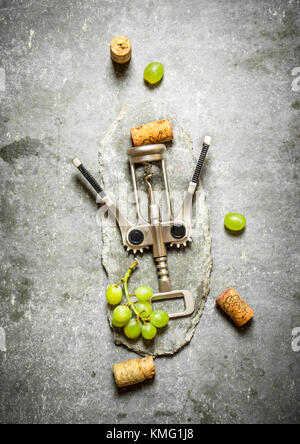 Wine corkscrew with grapes and corks. On the stone table. Stock Photo