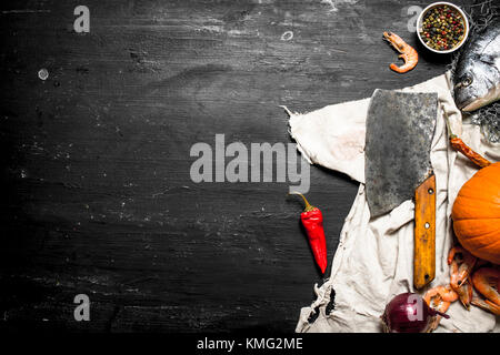 Fresh seafood. Seafood with vegetables and a large hatchet. On a black chalkboard. Stock Photo