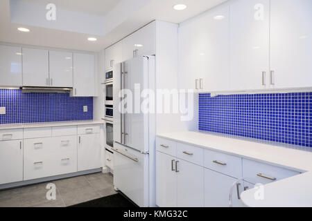 Kitchen interior remodel with blue tile walls and white countertops  and cabinets Stock Photo