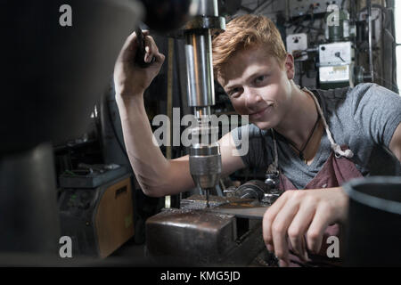 Portrait of blacksmith apprentice using drilling machine Stock Photo