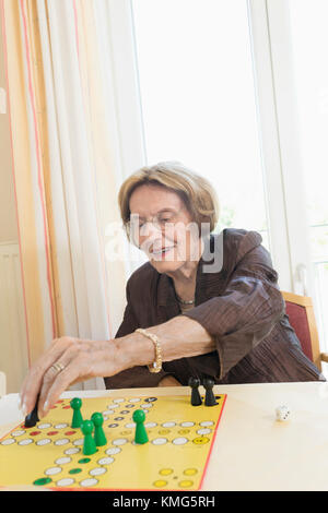 Senior woman playing board game in rest home Stock Photo