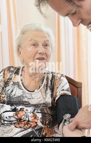Caretaker checking blood pressure of senior woman in rest home Stock Photo