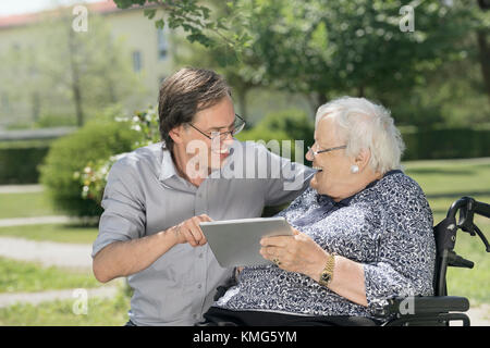 Son with disabled mother using digital tablet Stock Photo