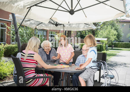 Multi-generation family playing board game at nursing home Stock Photo