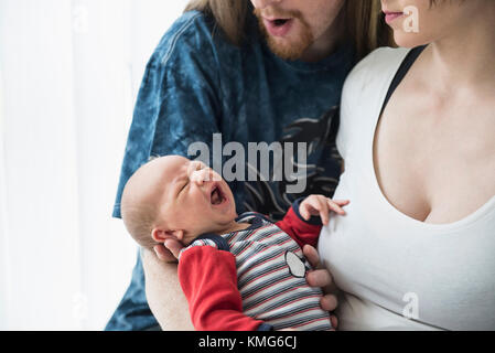 Parents holding crying baby boy in their arms Stock Photo