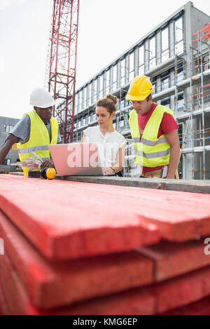Architect using laptop with construction worker at building site Stock Photo