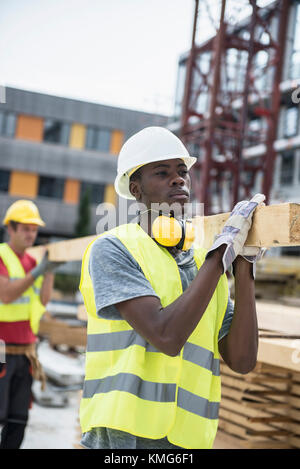 Construction workers carrying wooden planks at site Stock Photo