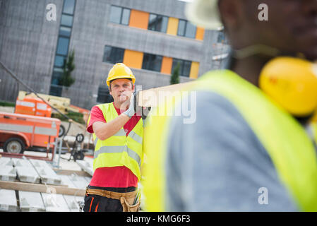 Construction workers carrying wooden planks at site Stock Photo