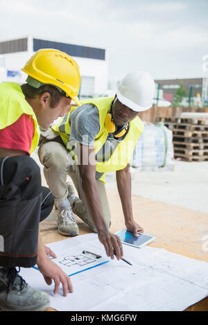 Construction workers reviewing blueprint at construction site Stock Photo