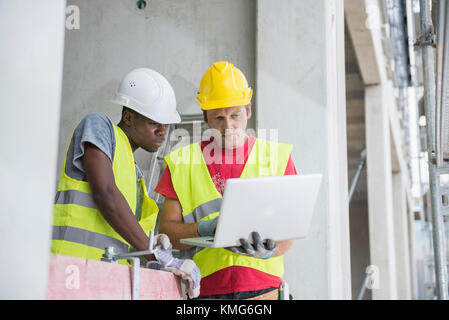 Construction workers using laptop at site Stock Photo