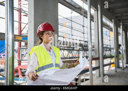 Female architect with blueprint at construction site Stock Photo