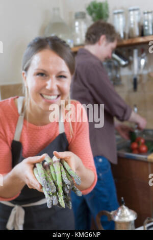 Couple preparing food, woman holding asparagus Stock Photo