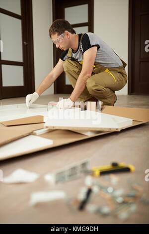Carpenter man assembling furniture in house. Assemble furniture theme Stock Photo