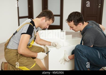 Two mans assembling furniture on floor of apartment Stock Photo