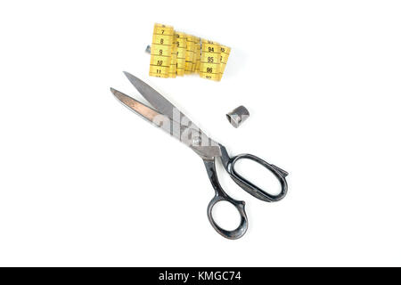 Old metal scissors and yellow measuring tape on white background Stock Photo