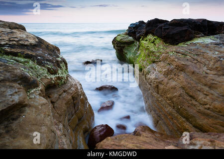 Silky sea water on rocky coastline Stock Photo