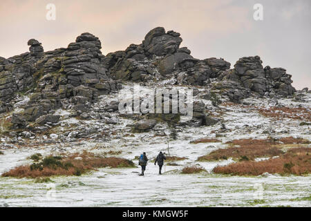 Hound Tor, Dartmoor, UK.  8th December 2017.  UK Weather.  Walkers enjoying the light dusting of snow which covers the landscape at Hound Tor in the Dartmoor National Park in Devon on a day of snow showers and cold temperatures.  Picture Credit: Graham Hunt/Alamy Live News Stock Photo