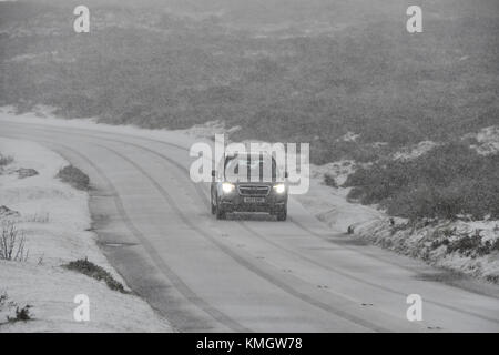 Haytor, Dartmoor, UK.  8th December 2017.  UK Weather.  A car driver taking it slowly as a heavy snow shower falls making driving treacherous on the B3387 near Haytor in the Dartmoor National Park in Devon. Picture Credit: Graham Hunt/Alamy Live News Stock Photo