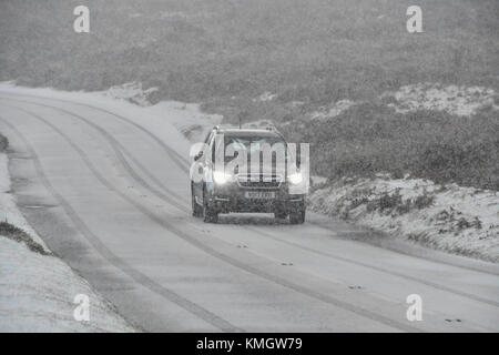 Haytor, Dartmoor, UK.  8th December 2017.  UK Weather.  A car driver taking it slowly as a heavy snow shower falls making driving treacherous on the B3387 near Haytor in the Dartmoor National Park in Devon. Picture Credit: Graham Hunt/Alamy Live News Stock Photo