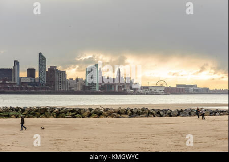 New Brighton, Wirral, UK. 8th December 2017. Pet owners walk their dogs on the beach as strong wind and rain hits New Brighton, on the Wirral peninsula, catching the tail end of storm Caroline. Cloud breaks over Liverpool in the distance. Credit: Paul Warburton/Alamy Live News Stock Photo