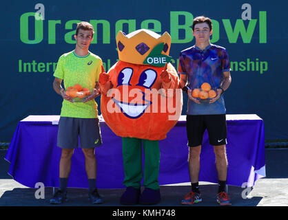 Plantation, Florida, USA. 10th Dec, 2017. Hugo GASTON (FRA), left, winner of the Boys 18s Final of the 2017 Orange Bowl International Tennis Championship, and Dostanbek TASHBULATOV (KAZ), right, finalist, pose OBIE, center, the official Orange Bowl mascot, as they hold their trophies during the championship's ceremony, at the Frank Veltri Tennis Center in Plantation, Florida, USA. Gaston defeated Tashbulatov 6-2, 6-3. Mario Houben/CSM/Alamy Live News Stock Photo